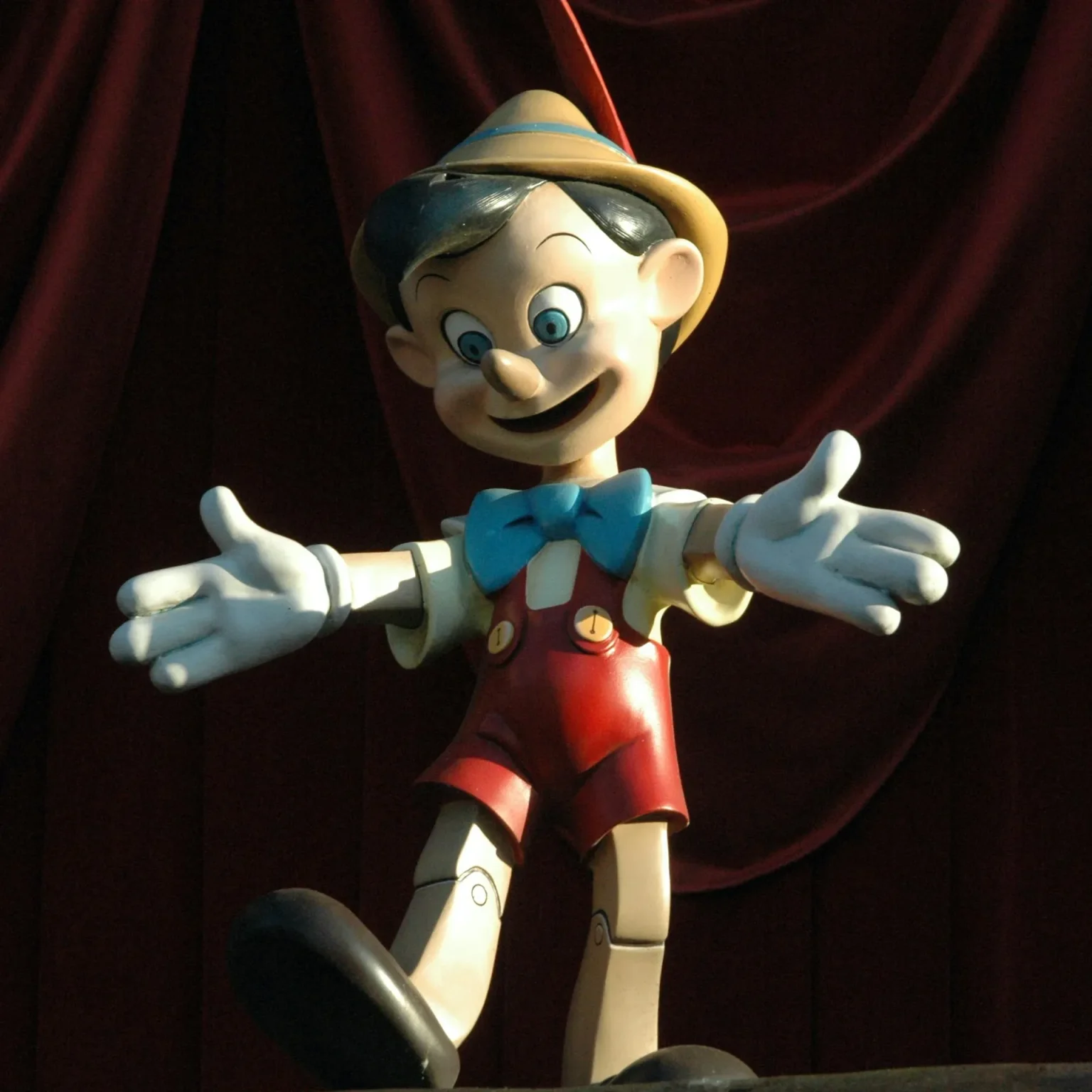 Pinocchio lächelt vor rotem Vorhang mit ausgebreiteten Armen